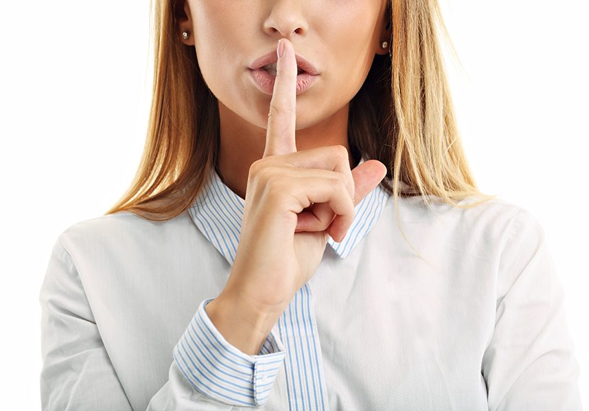 Adult woman holding a finger on her lips over white background Picture of adult woman holding a finger on her lips over white background
